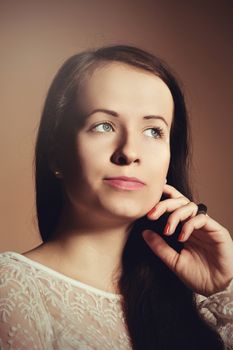 Fashion portrait of beautiful brunette young woman with perfect skin and long hair on beige background