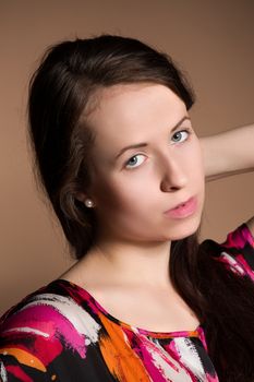 Fashion portrait of beautiful brunette young woman with perfect skin and long hair on beige background