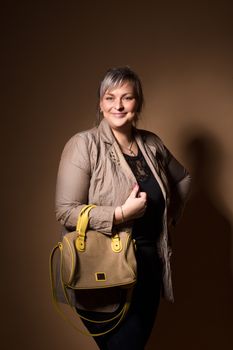 portrait of beautiful smiling plus size young blond woman posing with designer handbags