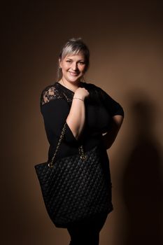 portrait of beautiful smiling plus size young blond woman posing with designer handbags and black dress