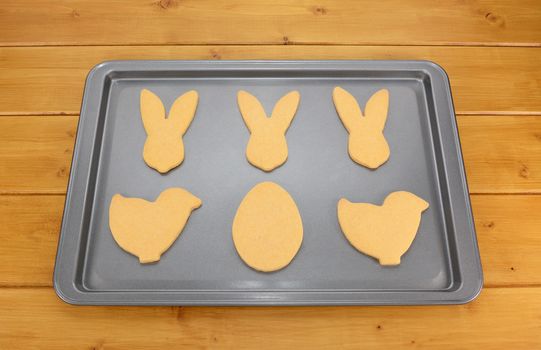 Cookie tray of Easter biscuits in rabbit, chick and egg shapes on a wooden table