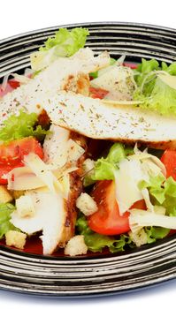 Caesar Salad with Grilled Chicken Breast, Garlic Crouton, Lettuce, Tomatoes and Grated Parmesan Cheese on Striped Plate closeup on white background