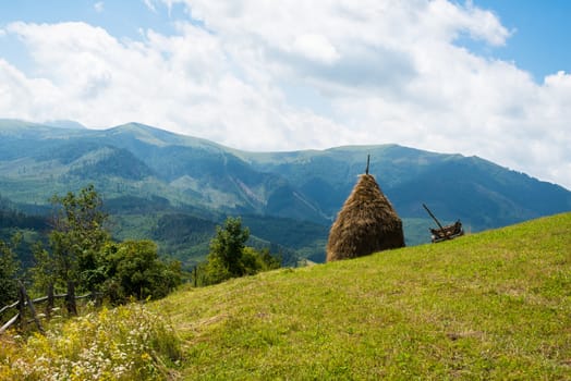 Haystack and wooden cart against the summer landscape in the Ukrainian Carpathians