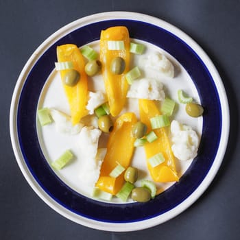 Dish of vegetables including yellow pepper, celery, cauliflower and olive