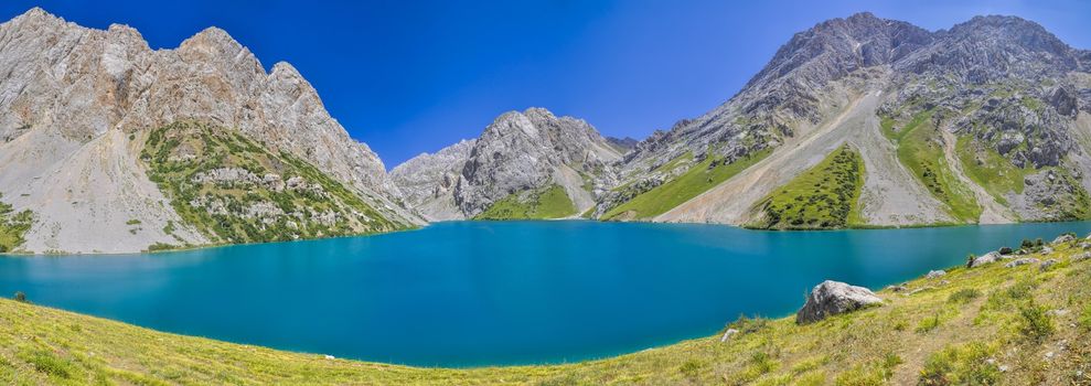 Scenic panorama of turquoise lake in picturesque mountains in Kyrgyzstan