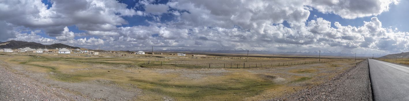 Scenic panorama of small village on remote green grasslands in Tajikistan