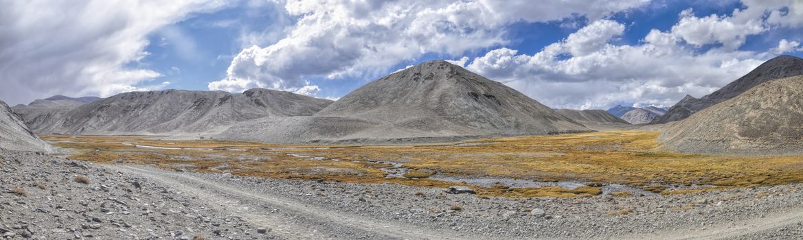 Scenic panorama of dirt road leading through arid landscape in Tajikistan