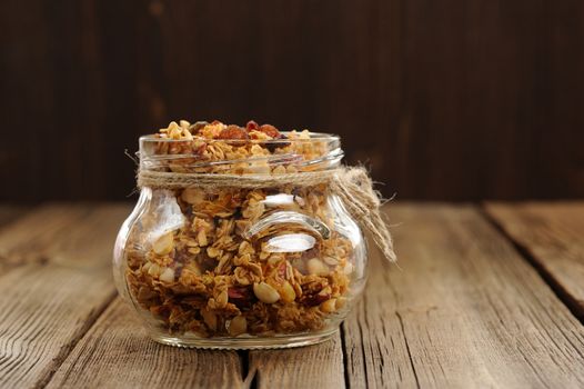 Granola in jar with packing-twine on wooden background with space horizontal