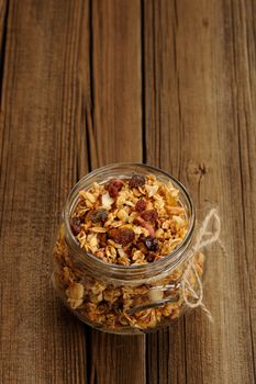 Granola in jar with packing-twine on wooden background with space vertical