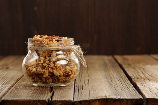 Granola in jar with packing-twine on wooden background with space horizontal