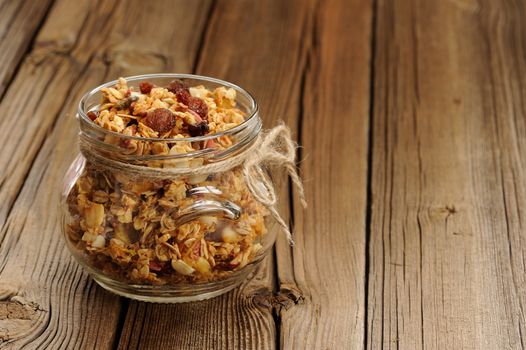 Granola in jar with packing-twine on wooden background with space horizontal