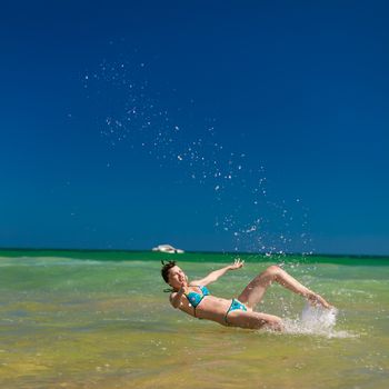 Yong happy woman splashing water in the ocean