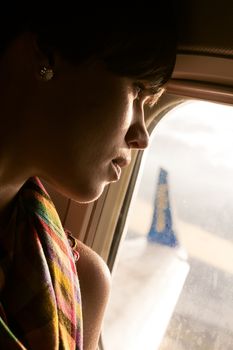 female airplane passanger enjoying the view from the cabin window over the blue sky