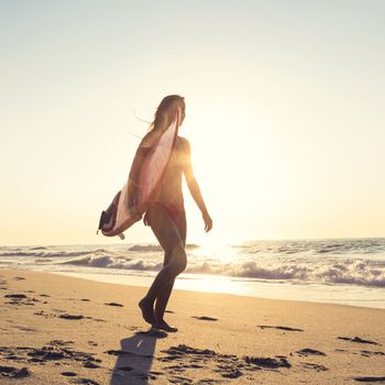 Beautiful young girl in the beach with her surfboard