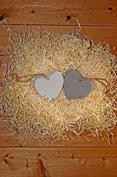 two blank grey wooden love hearts in a love nest made of straw with copy space