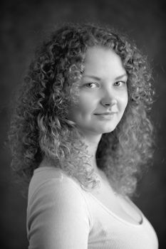 Smiling fairy woman with curly hair, big breast, low neck decollete on dark grey background black&white vertical portrait