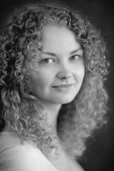 Smiling fairy woman with curly hair, big breast on dark grey background black&white vertical portrait