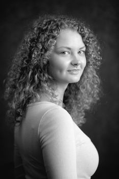 Smiling fairy woman with curly hair, big breast on dark grey background black&white vertical portrait