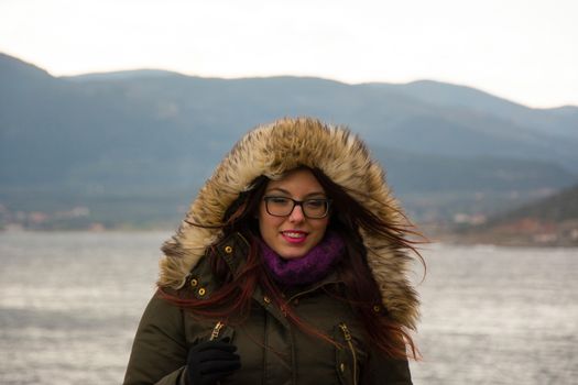 A young girl on a winter excursion standing in front of the sea.