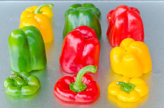 Red, Green, Yellow Bell Pepper on silver background.