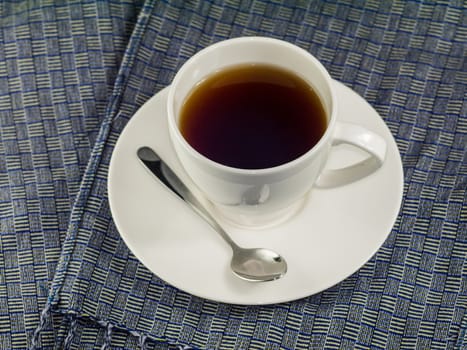 A white cup of hot tea with spoon