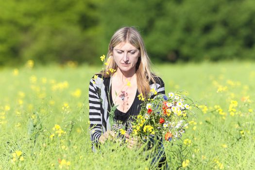 Woman Picking Wild Flowers on the Meadow in Spring
