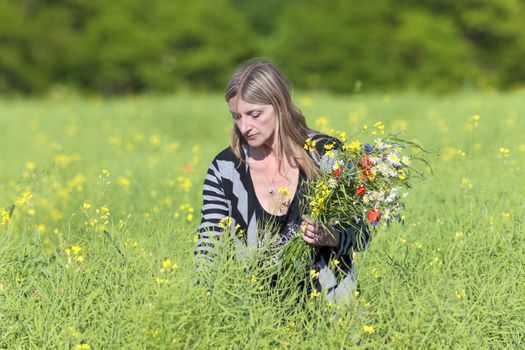 Woman Picking Wild Flowers on the Meadow in Spring