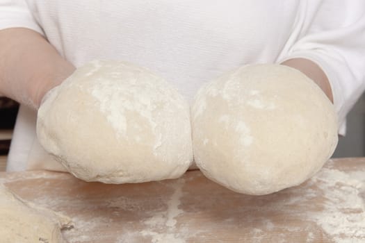 Baker Holding up Two Loafs of Bread Ready for Baking