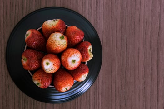 Bowl of fresh succulent strawberries over wood