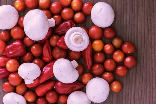 Many cherry tomatoes mushrooms and chili over wood