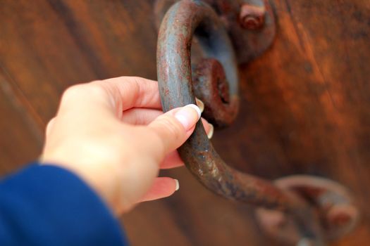 Old rusty doorknob and a female hand