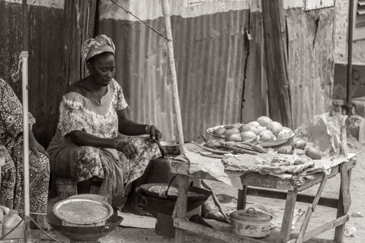 Mbour, Senegal - July, 2014: A woman selling food on the street roasts peanuts in a wok on July 9, 2014 in Mbour, Senegal.