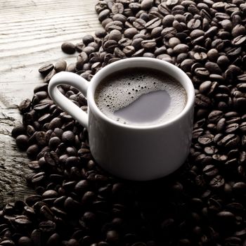 Coffee cup and roasted beans on wooden table