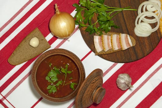 Traditional Ukrainian soup in pottery served with salted lard on rye bread