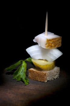 Canape with salted lard, onion, pickled cucumber, rye bread and parsley