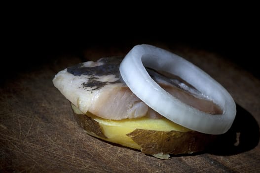 Piece of salted herring on slice of boiled jacket potato