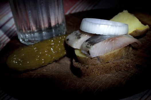 Sandwich made of herring on boiled jacket potato and rye bread served with vodka