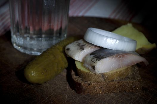 Sandwich made of herring on boiled jacket potato and rye bread served with vodka