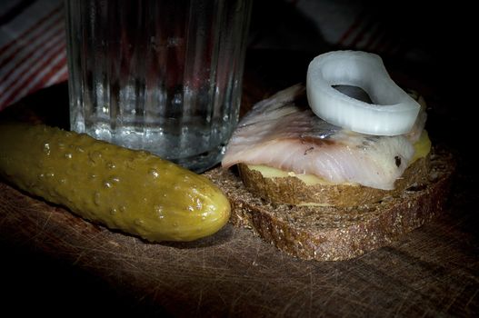 Sandwich made of herring on boiled jacket potato and rye bread served with vodka