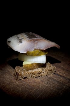 Canape made of herring, pickled cucumber, onion, jacket potato and rye bread