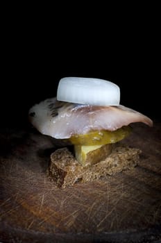 Canape made of herring, pickled cucumber, onion, jacket potato and rye bread