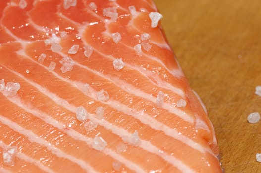 Fresh salmon fillet salted with coarse sea salt close up