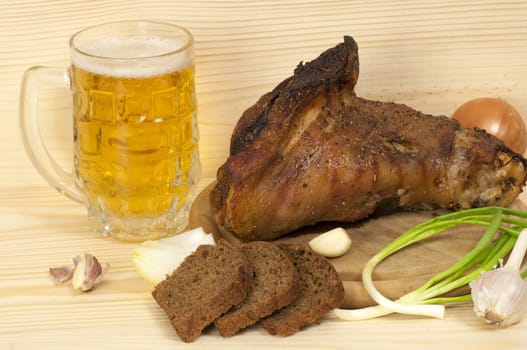 Roasted pork leg served with mug of beer, onion, rye bread and garlic