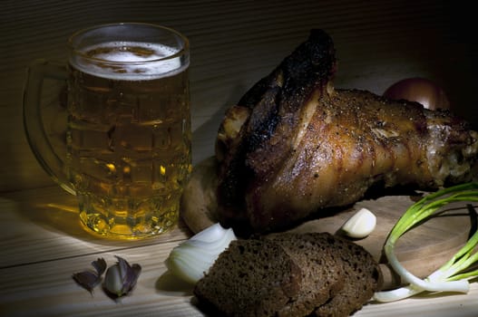 Roasted pork leg served with mug of beer, onion, rye bread and garlic