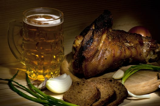 Roasted pork leg served with mug of beer, onion, rye bread and garlic