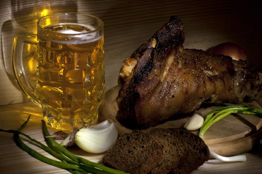 Roasted pork leg served with mug of beer, onion, rye bread and garlic