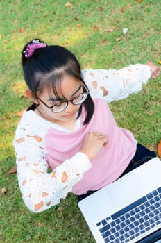 Cute girl is happy with notebook on grass in park