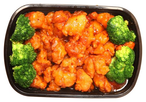 To go or delivery container of general tso chicken and broccoli. Top view over white.