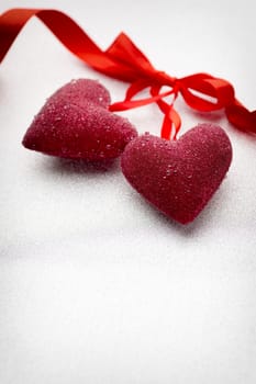 Red hearts tied with a ribbon on a silver background.