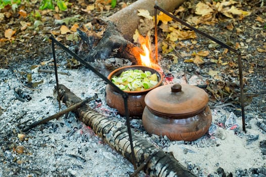 The roast in a clay pot over charcoal fire in nature